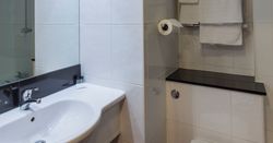 Modern bathroom with white sink, toilet, towels, and tiled walls