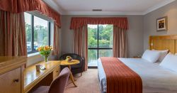 Comfortable hotel room with large bed, desk, and views of greenery outside.
