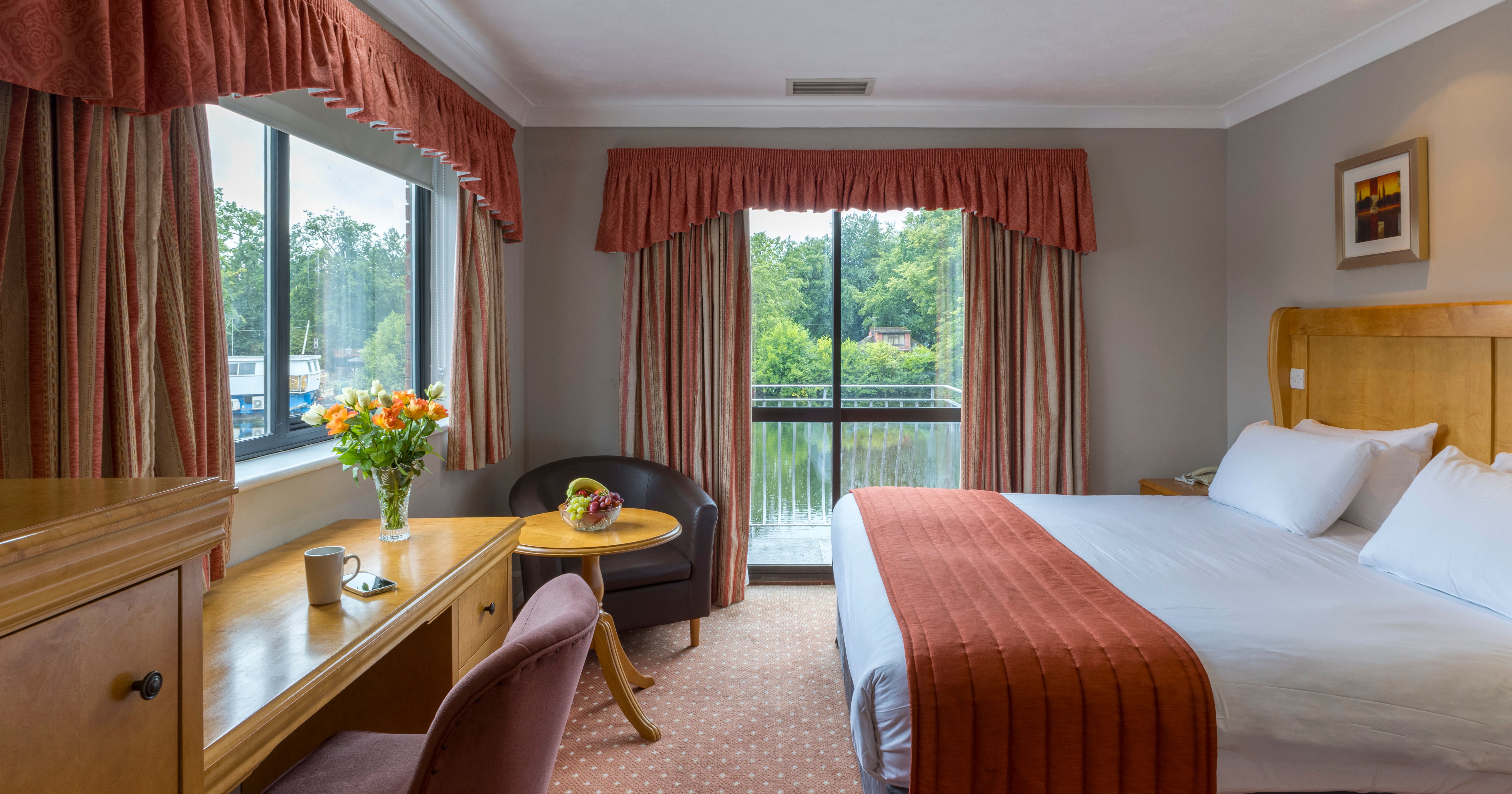 Comfortable hotel room with large bed, desk, and views of greenery outside.