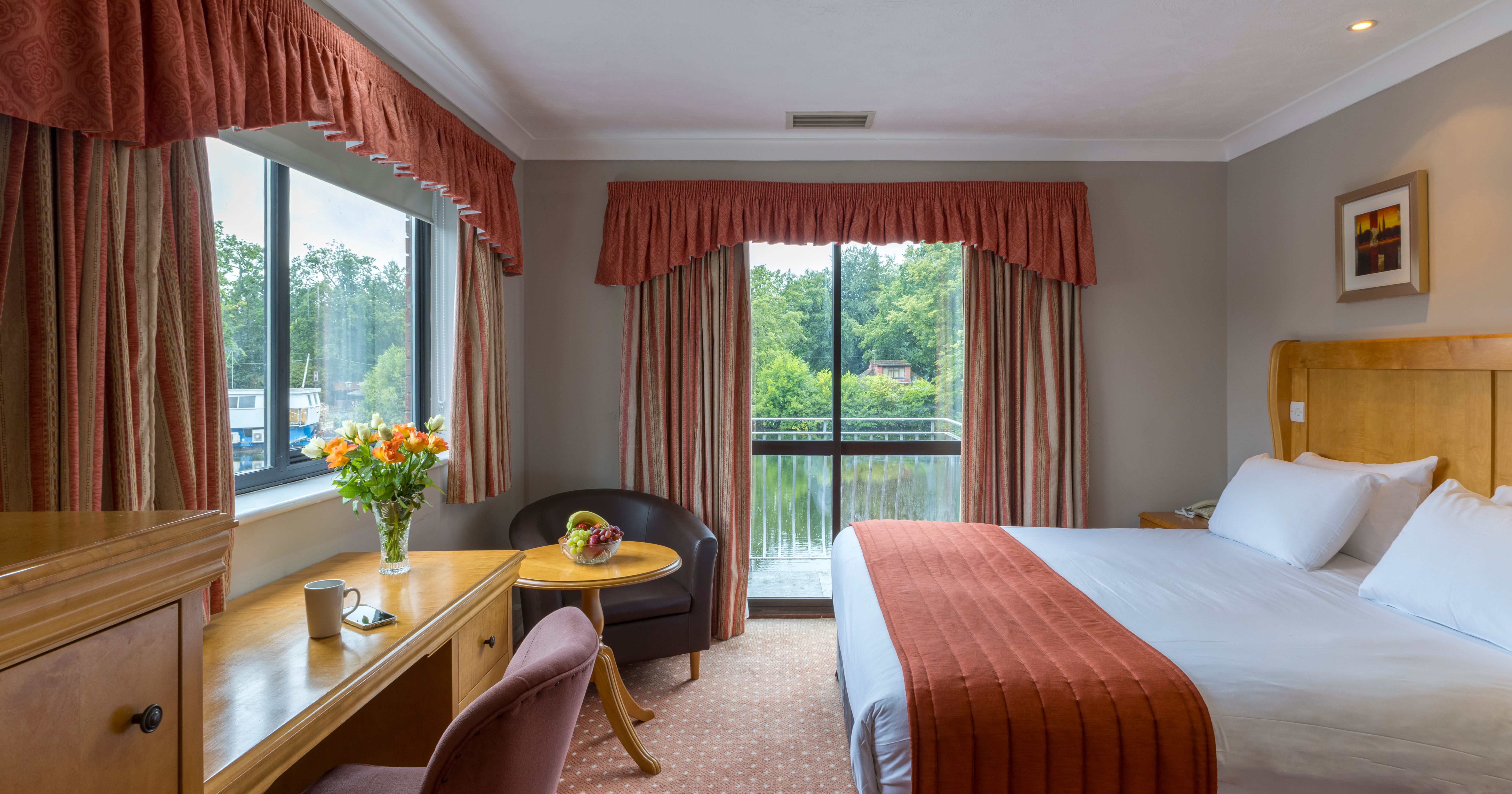 Comfortable hotel room with large bed, desk, and views of greenery outside.