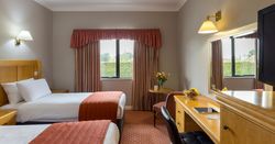 Hotel room with two beds, a desk, TV, and window with curtains