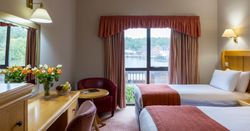 Hotel room with two beds, a window view, desk, flowers, and armchairs