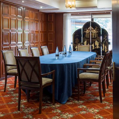 Elegant conference room with wooden paneling, blue tablecloth, and decorative folding screen.