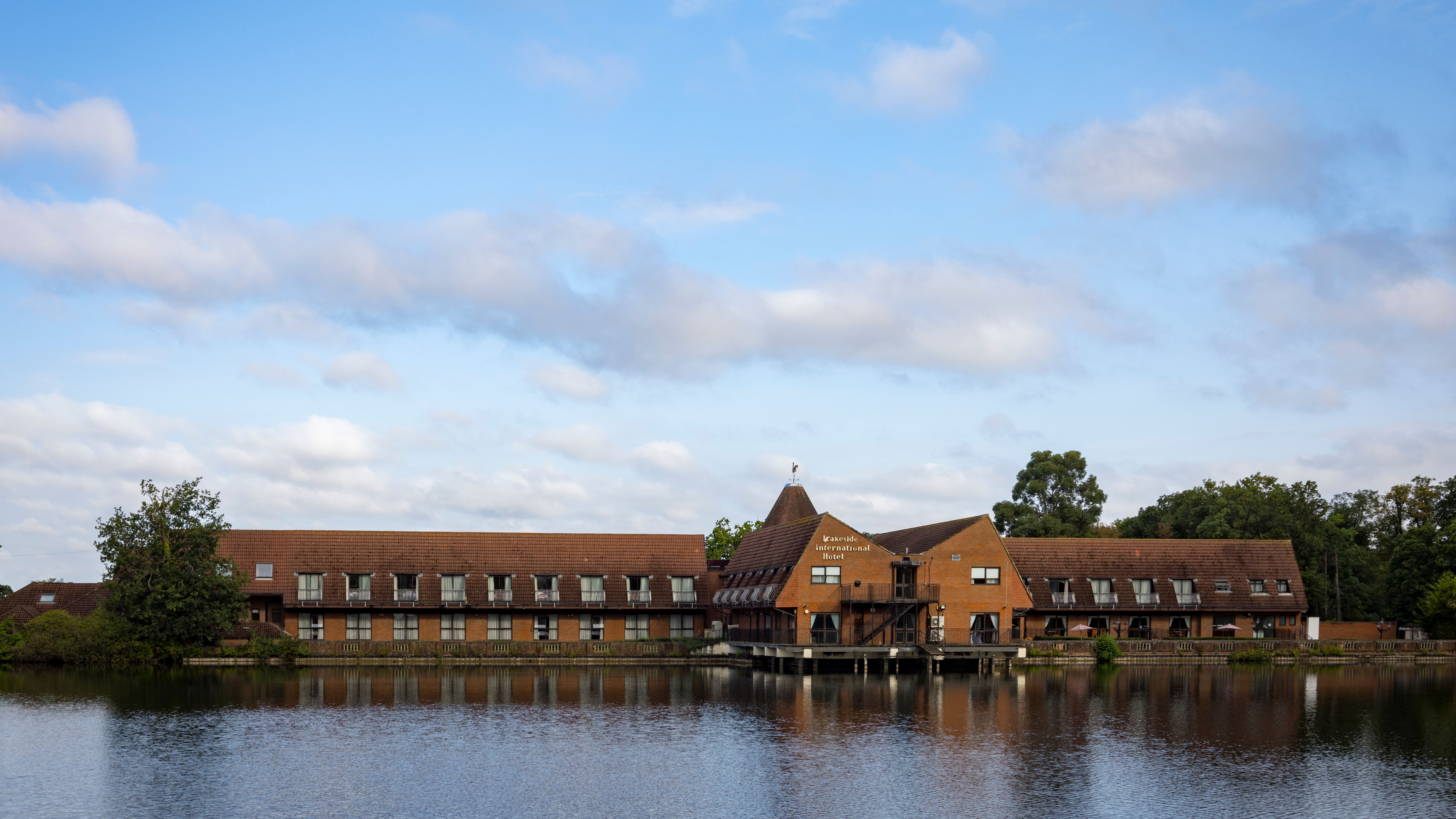 Lakeside International Hotel building by a lake under a blue sky with clouds