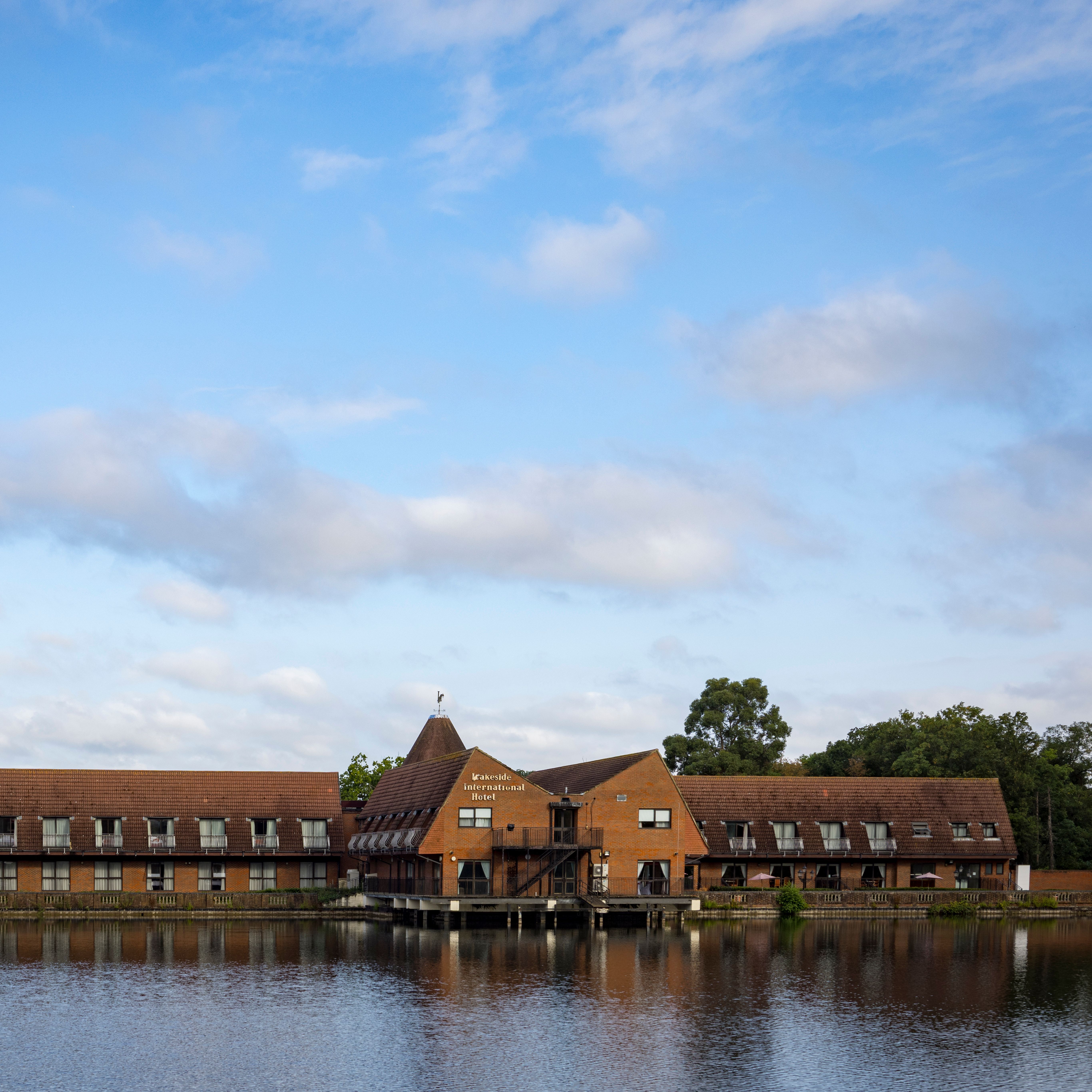 Lakeside International Hotel building by a lake under a blue sky with clouds