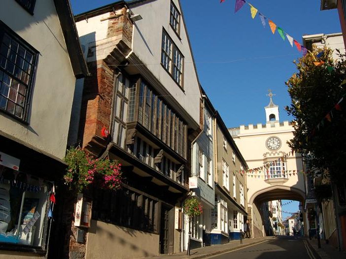 Street view in Totnes with historic timber-framed buildings and a clock archway decorated with bunting