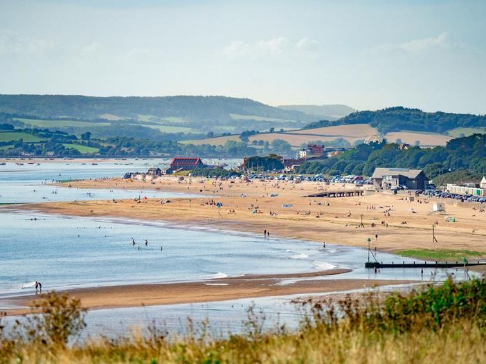 Wide view of Exmouth beach with golden sand, calm sea and distant green hills