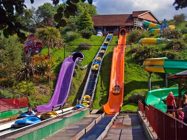 Water park ride with colourful slides and log flume boats on a hillside