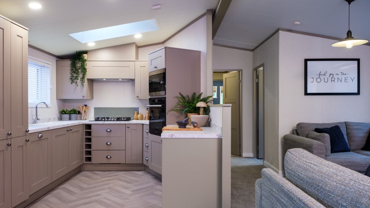 Modern open-plan kitchen and living area with grey cabinets, skylight and sofa