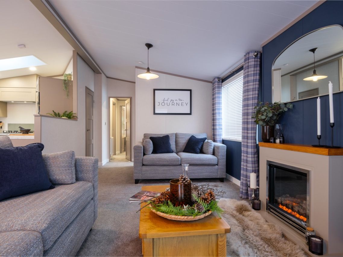 Modern living room with grey sofas, a wood coffee table and an electric fireplace on a blue feature wall