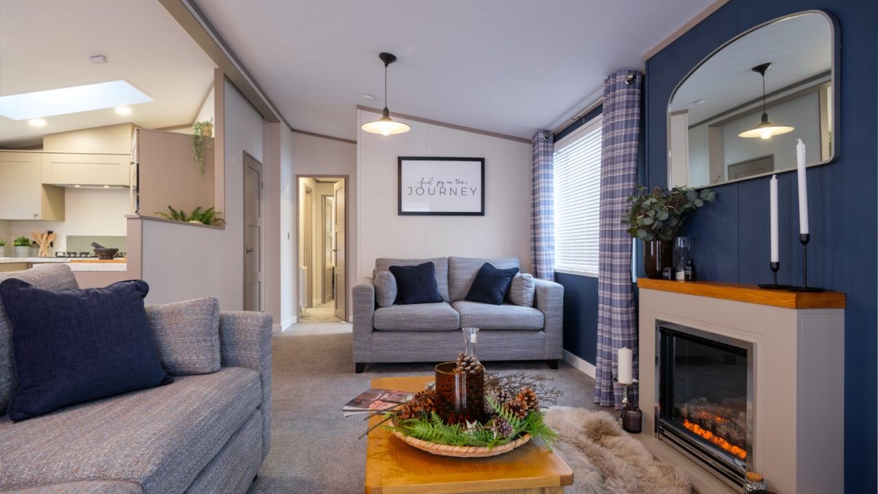 Modern living room with grey sofas, a wood coffee table and an electric fireplace on a blue feature wall