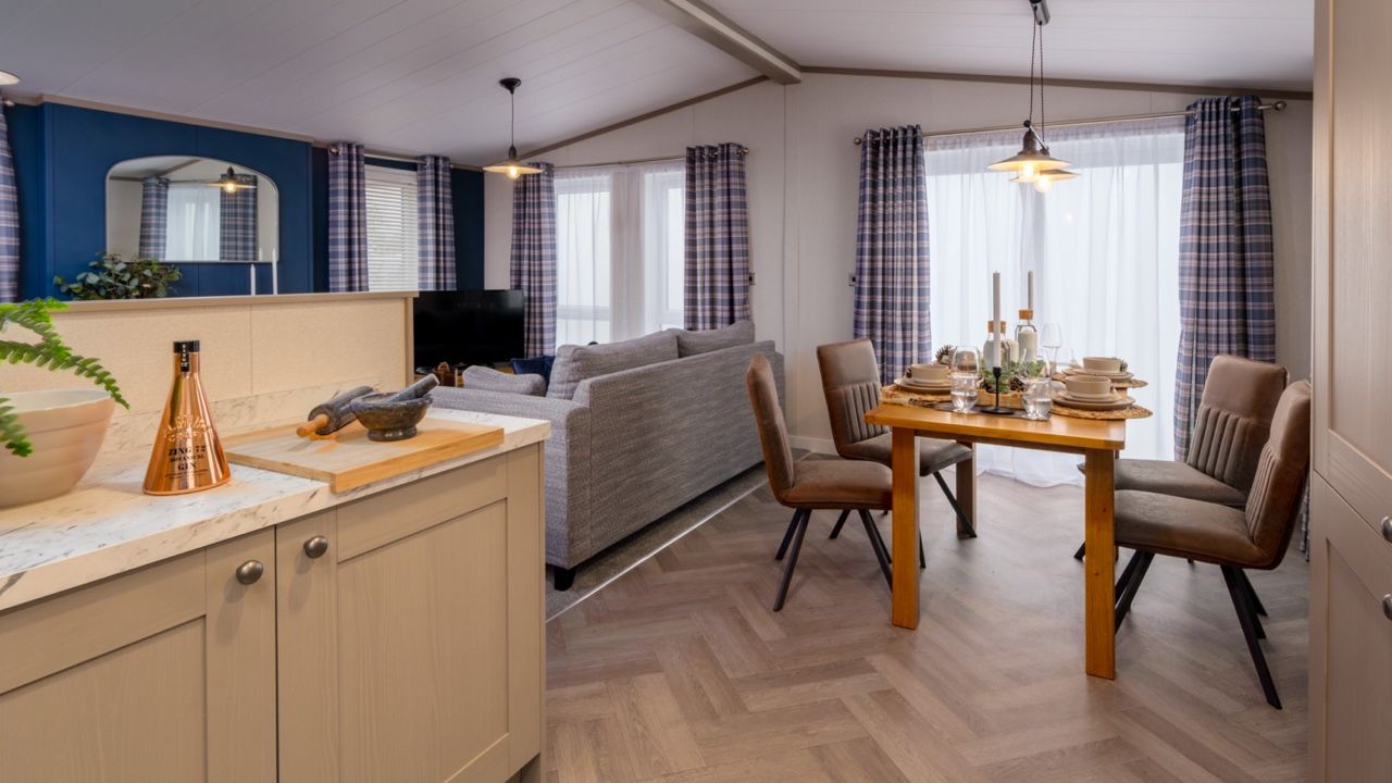 Open-plan kitchen, dining and living area with grey sofa and set dining table