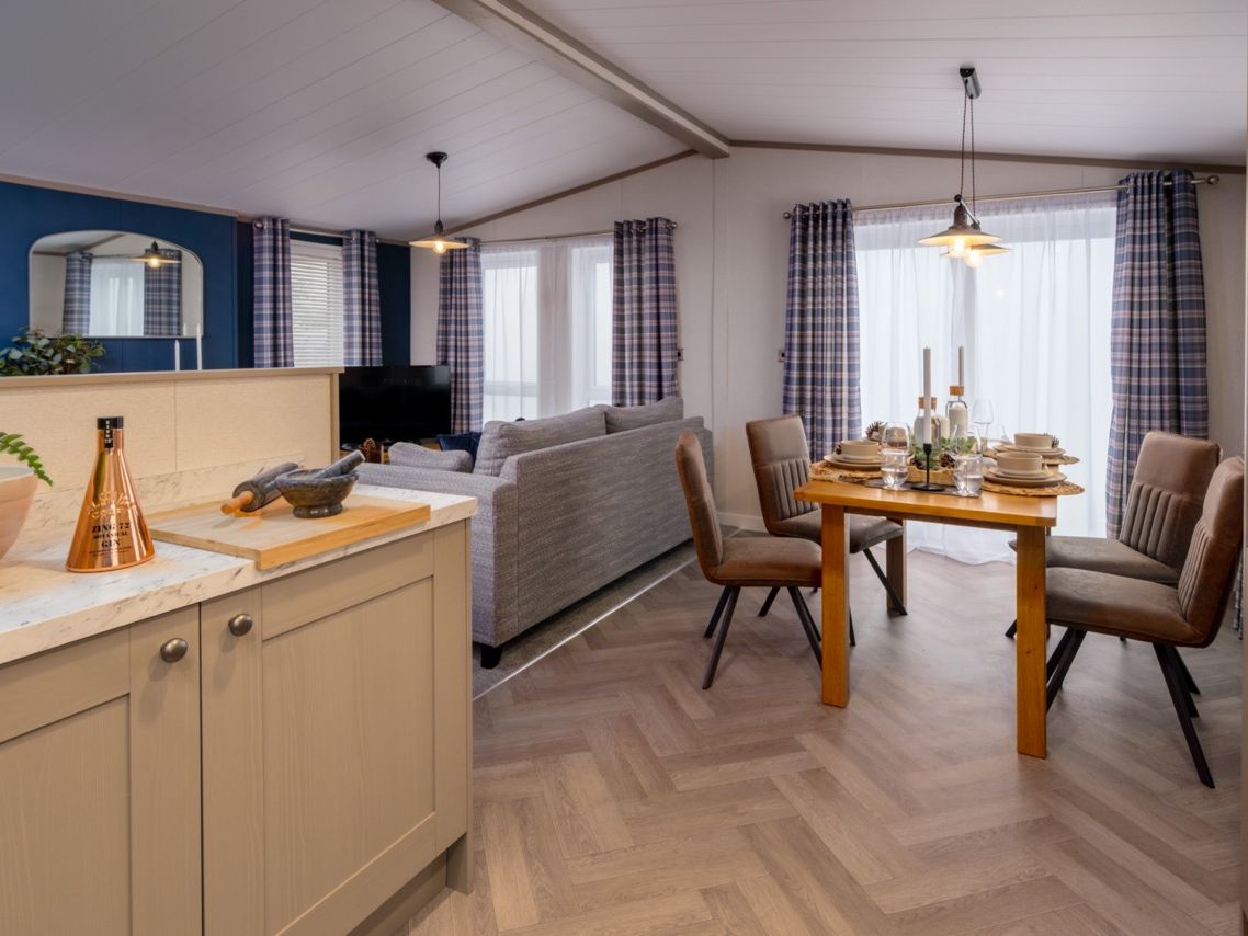 Open-plan kitchen, dining and living area with grey sofa and set dining table
