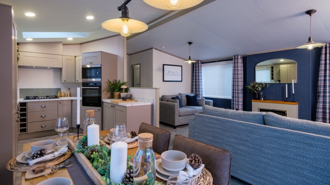 Open-plan kitchen, dining and lounge area with grey cabinetry, set dining table and blue accent wall