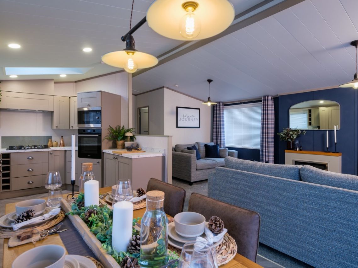 Open-plan kitchen, dining and lounge area with grey cabinetry, set dining table and blue accent wall