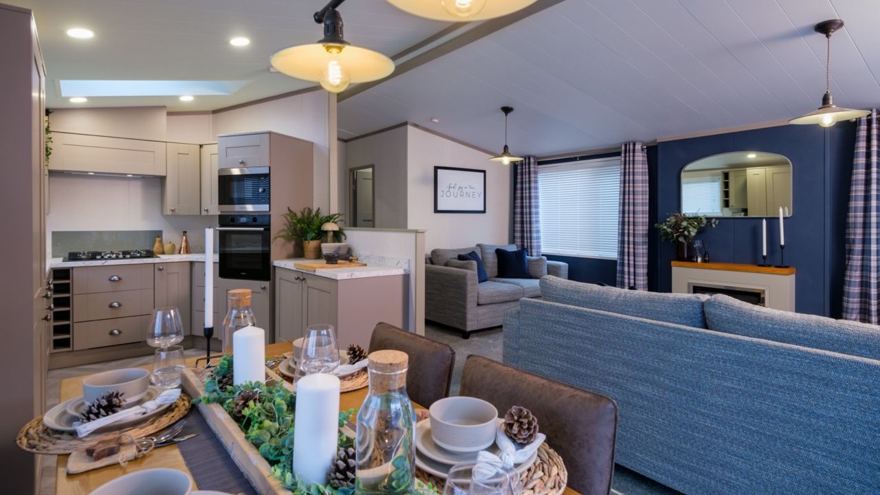 Open-plan kitchen, dining and lounge area with grey cabinetry, set dining table and blue accent wall