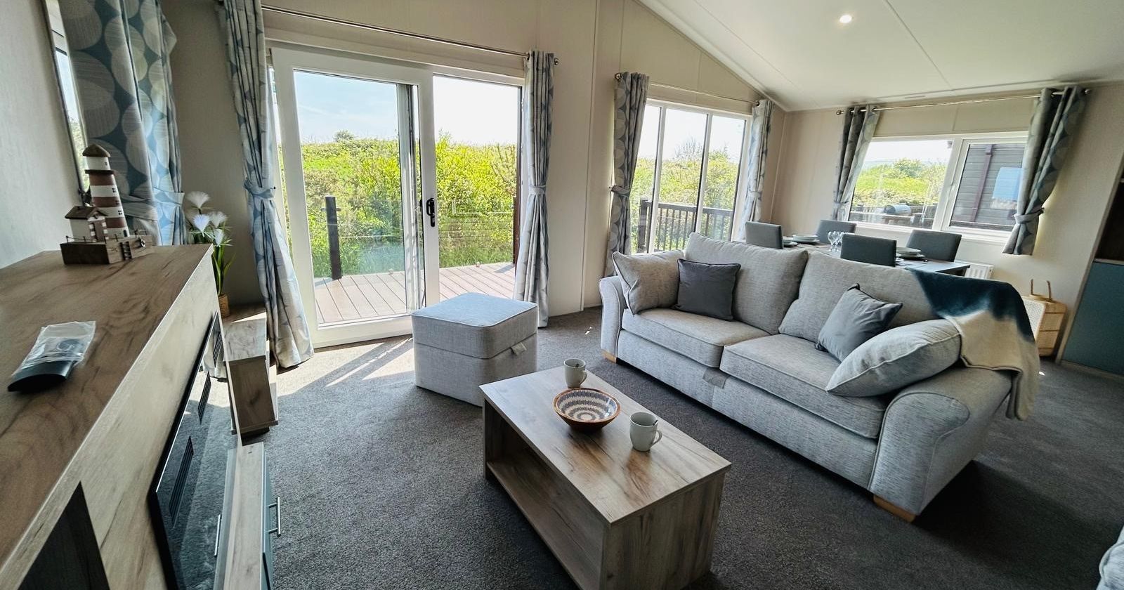 Bright modern living room with grey sofa, wooden coffee table and French doors to a balcony