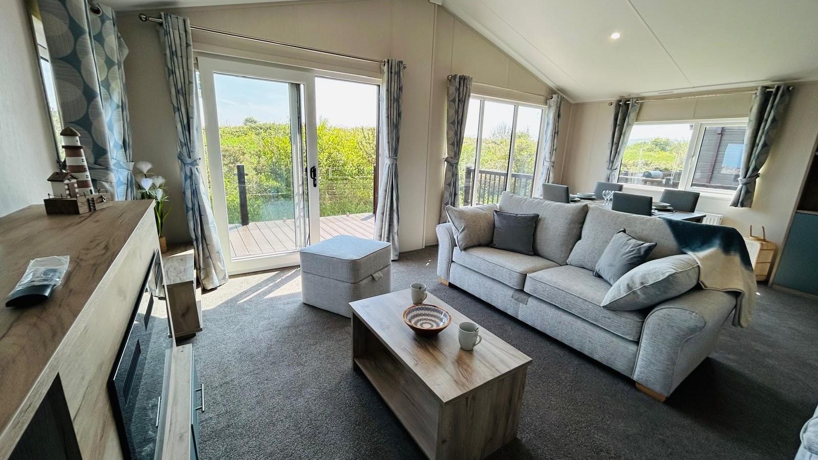 Bright modern living room with grey sofa, wooden coffee table and French doors to a balcony