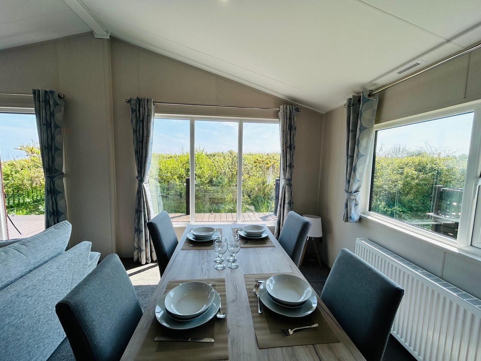 Dining table set for four beside large windows in a modern holiday lodge
