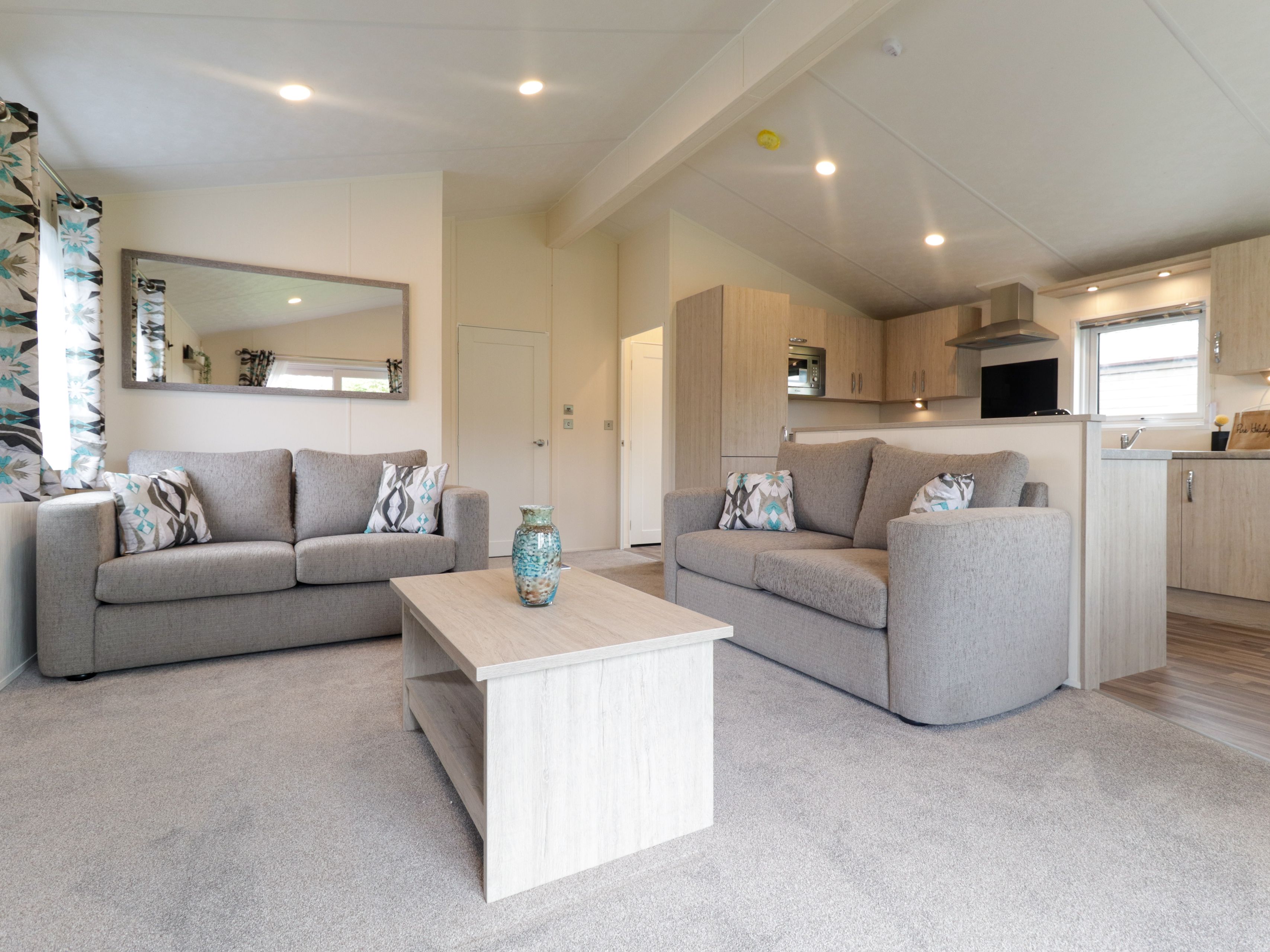 Modern open-plan living room and kitchen with two grey sofas and a light wood coffee table