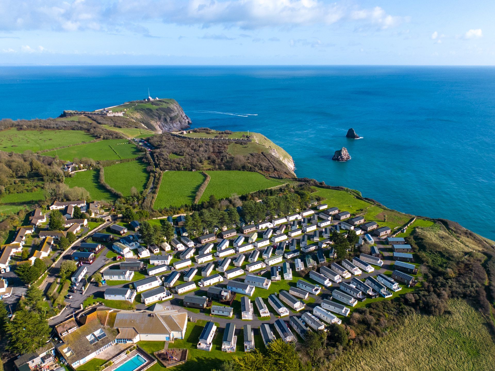 Drone view of Landscove holiday park on a coastal headland with green fields and blue sea