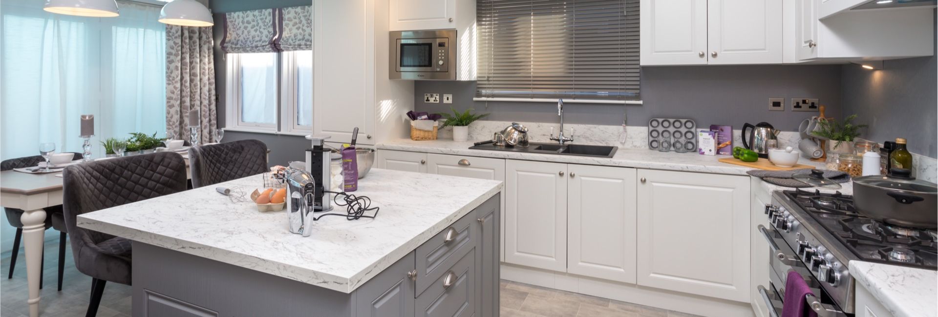 Modern kitchen with white cabinets, grey island and pendant lights under a skylight