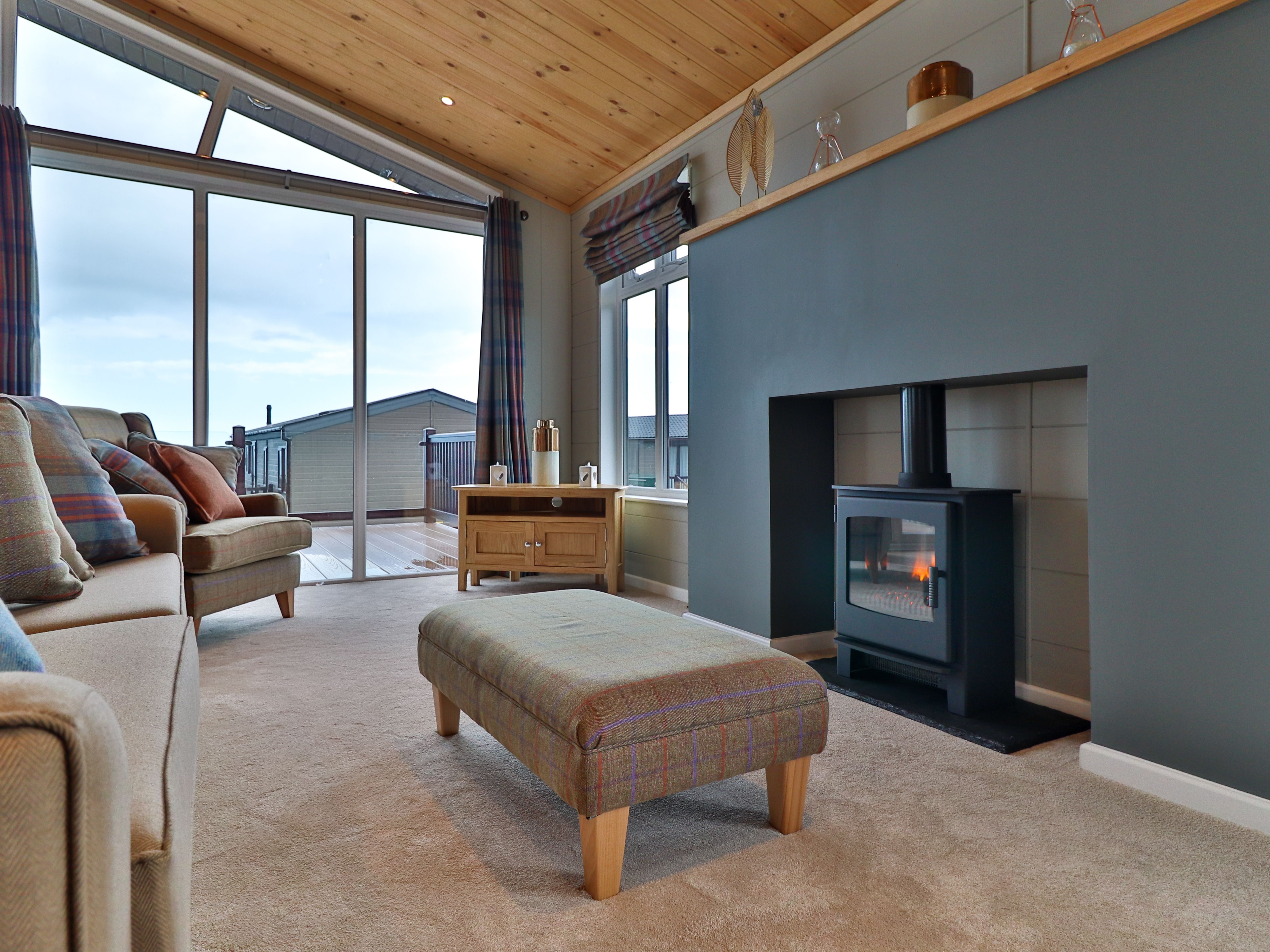 Cosy living room with wood-burning stove, large windows and sofa seating