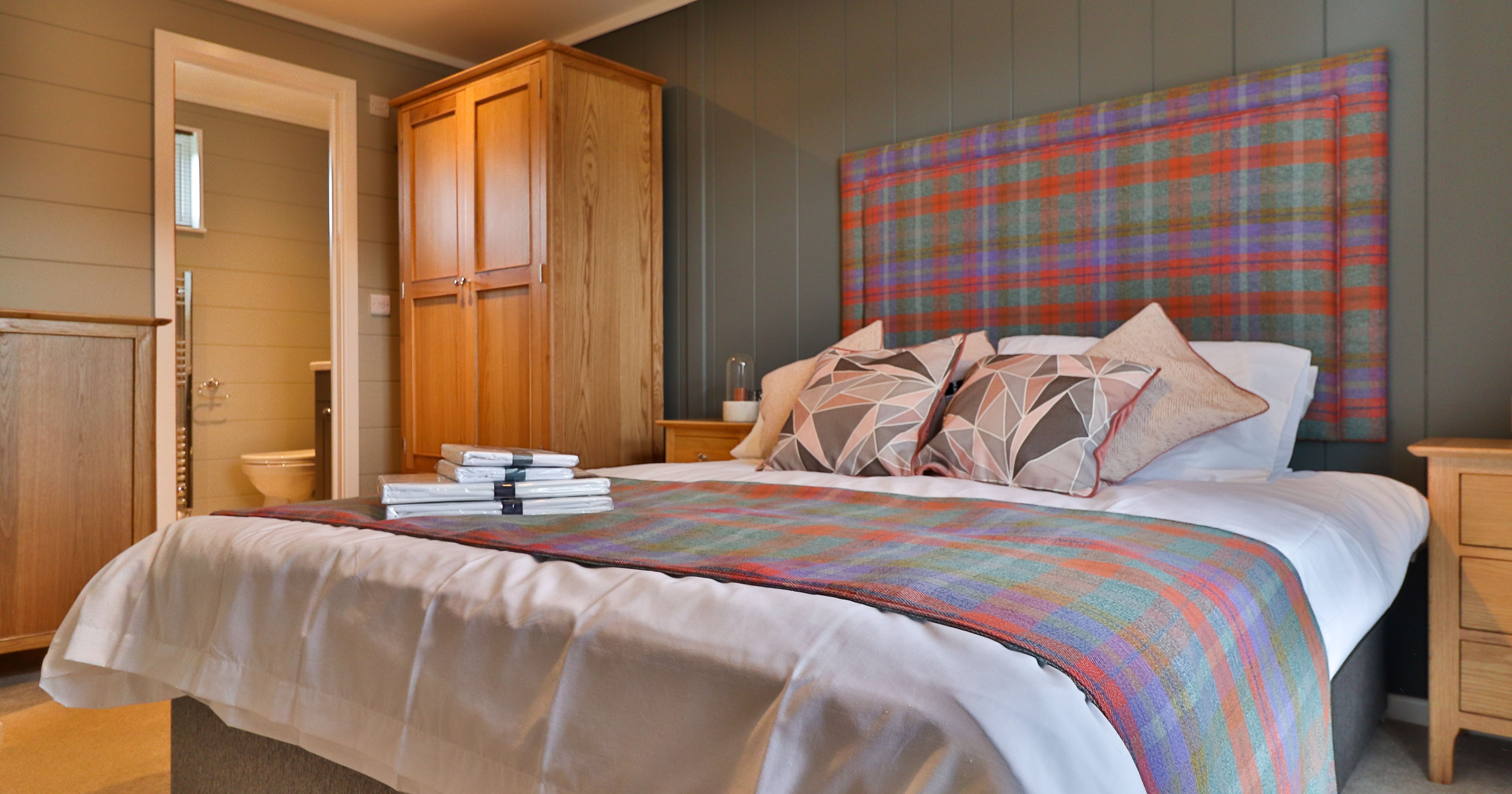 Cosy bedroom with tartan headboard, double bed and wooden wardrobe