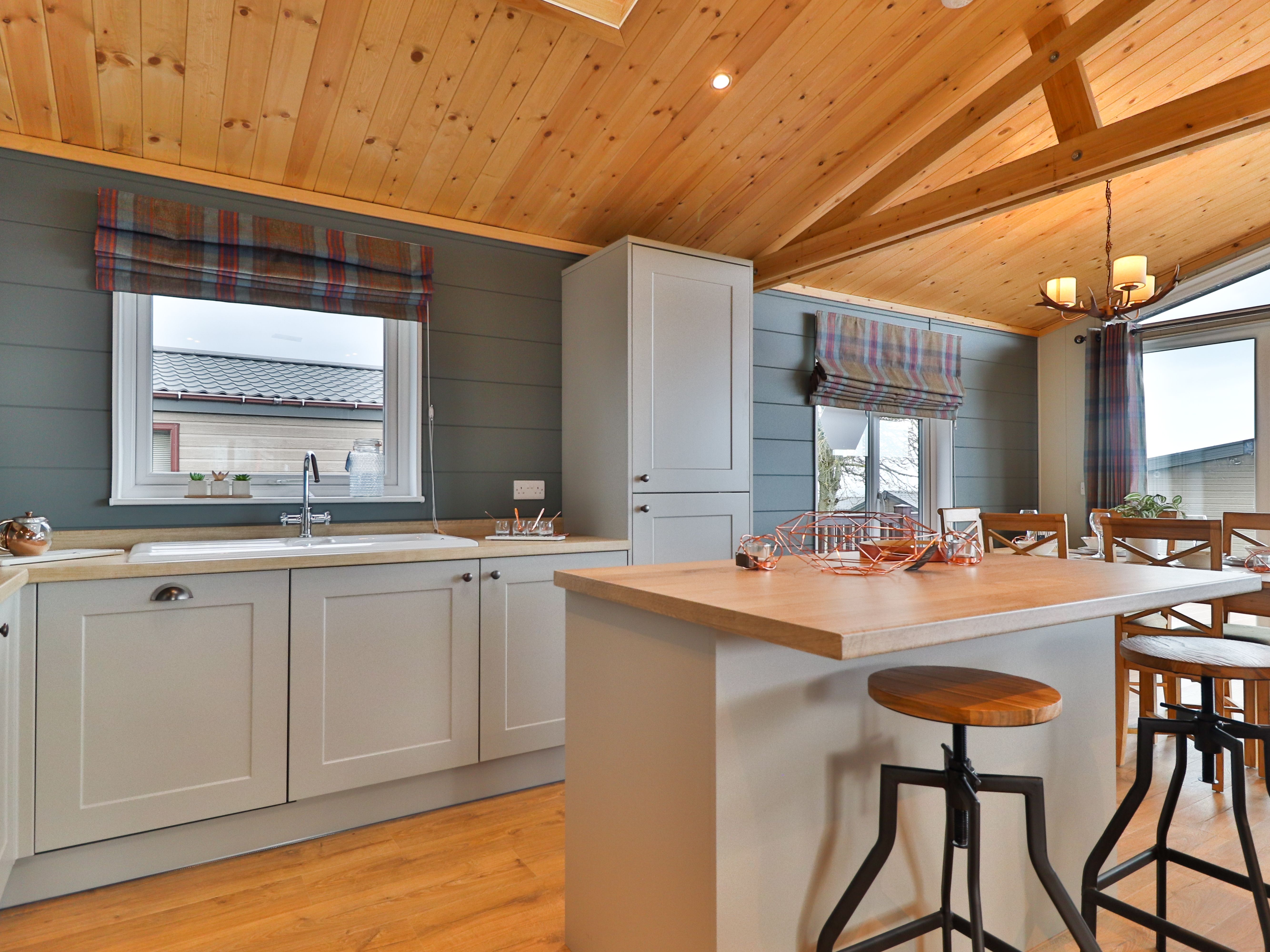 Modern kitchen and dining area with grey cabinets, wooden ceiling and a breakfast island