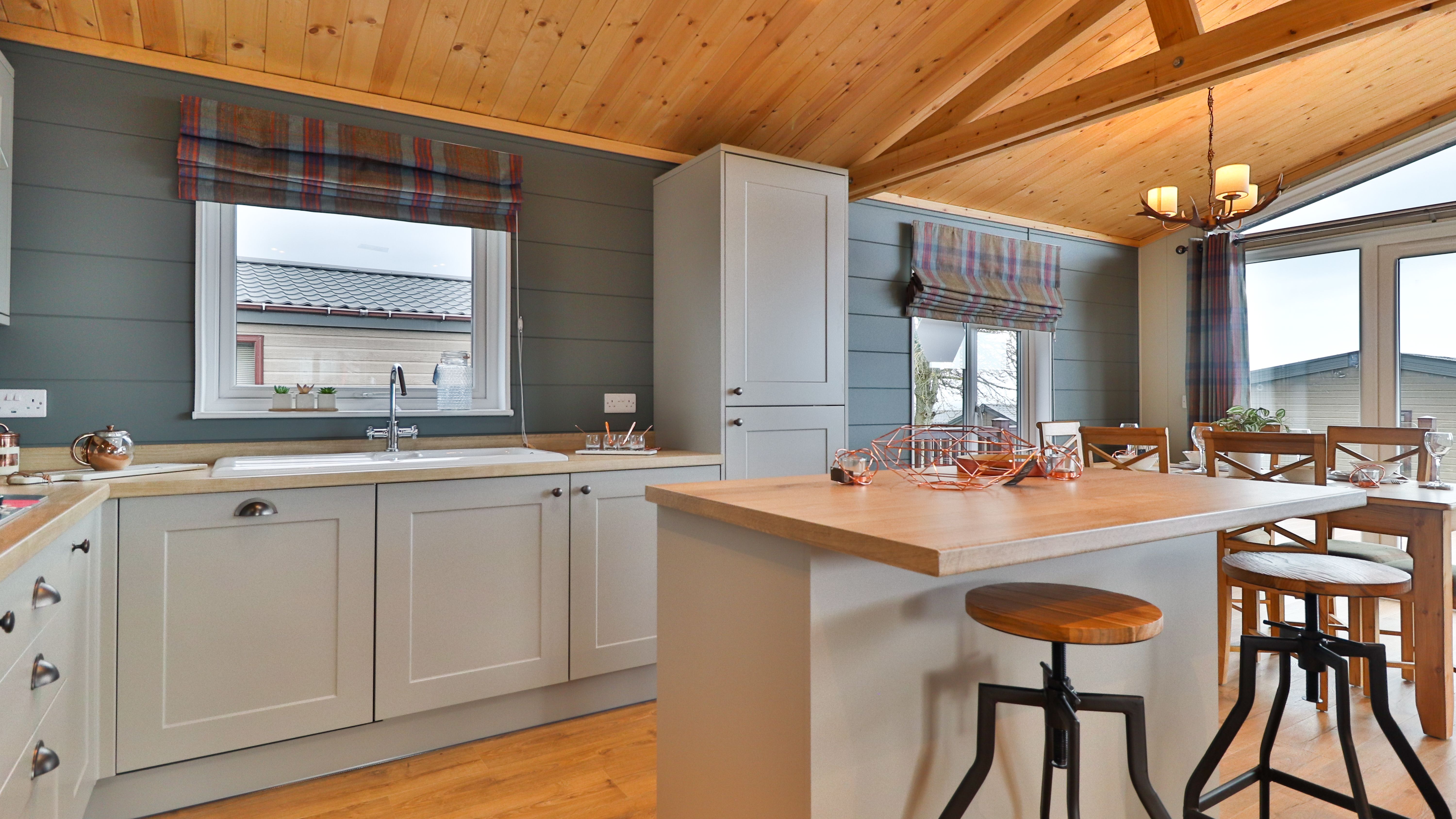 Modern kitchen and dining area with grey cabinets, wooden ceiling and a breakfast island