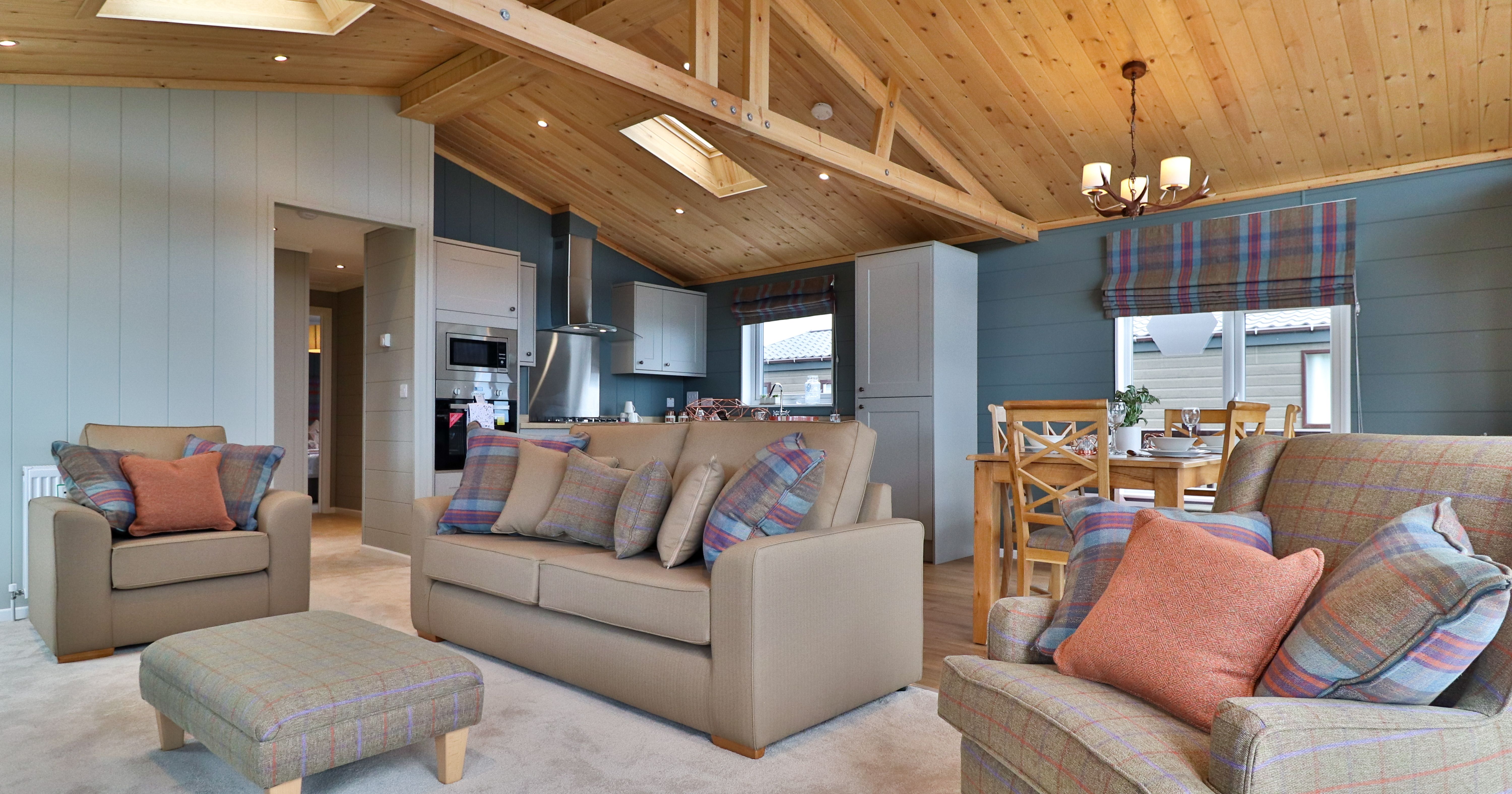 Cosy open-plan living room and kitchen with wooden vaulted ceiling, sofas and dining table