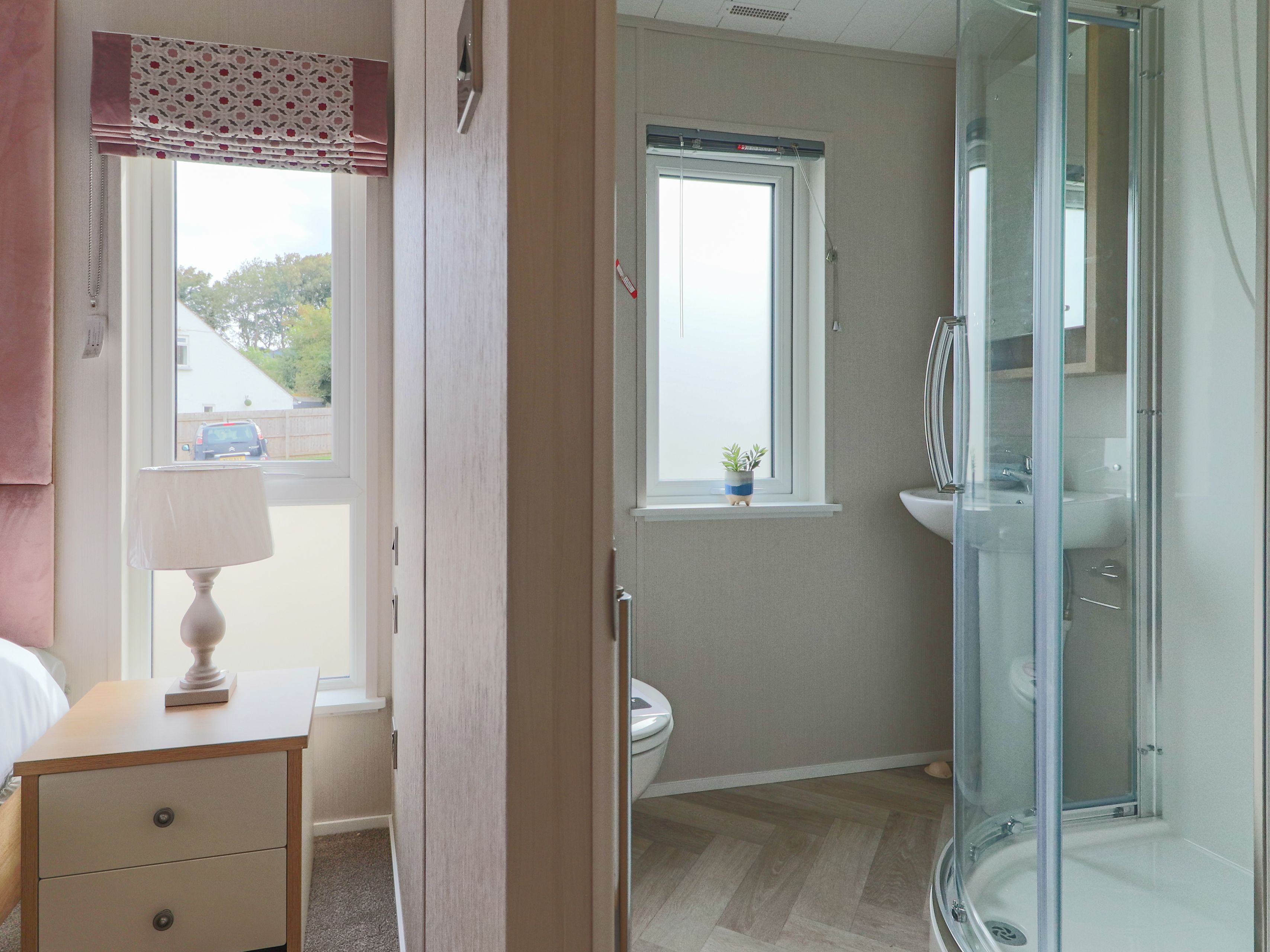 Bedroom and en-suite bathroom with bedside table, lamp, wardrobe and glass shower enclosure
