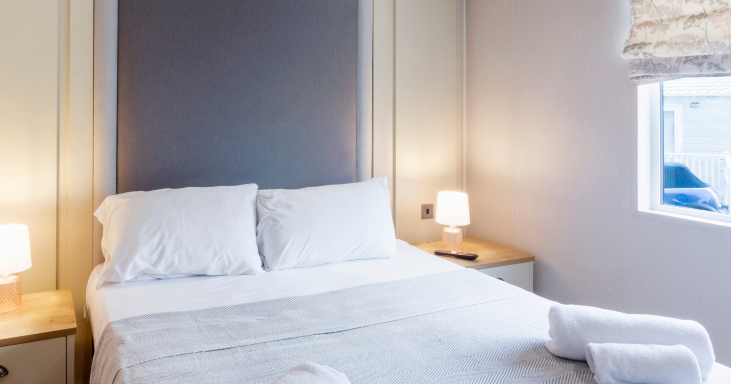Neat bedroom with double bed, white bedding and bedside lamps