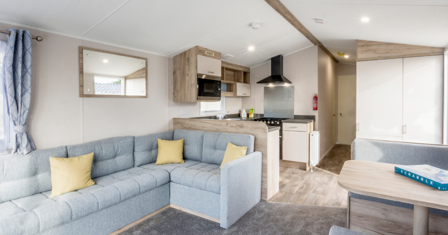 Modern caravan living area with corner sofa, kitchenette and dining table