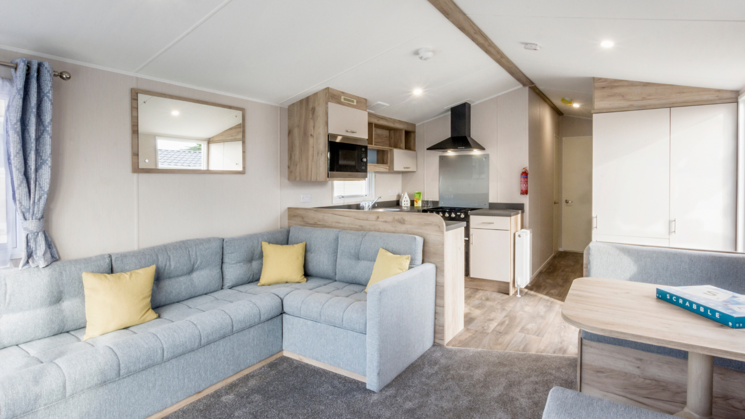 Modern caravan living area with corner sofa, kitchenette and dining table