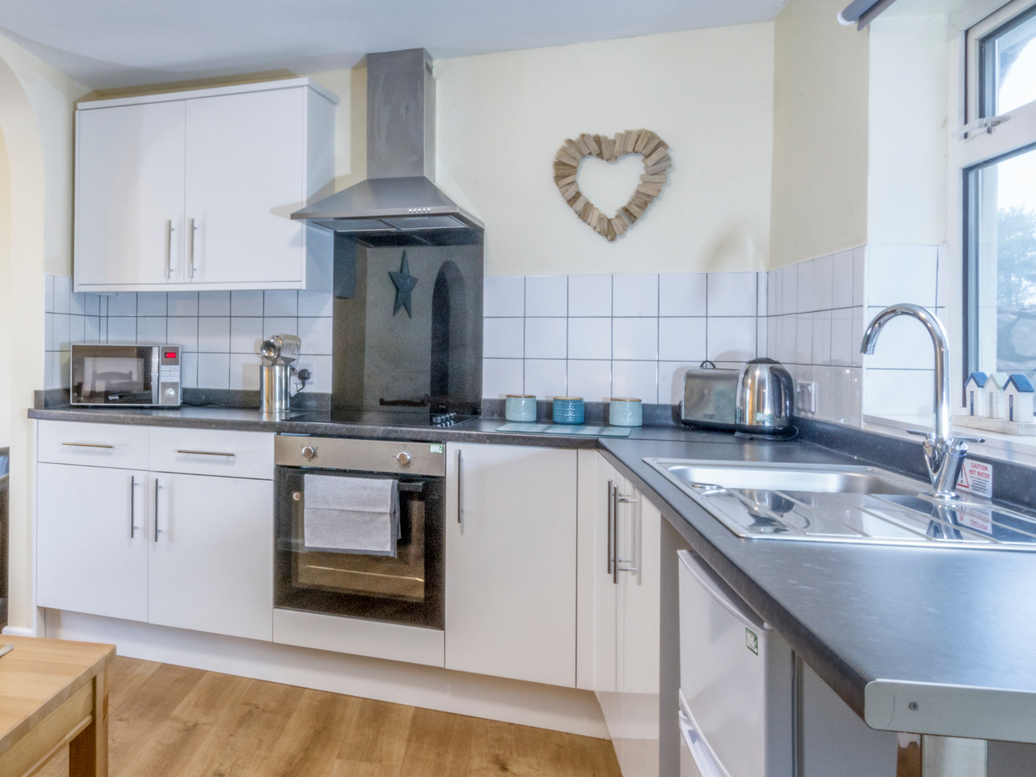 Modern white kitchen with stainless steel oven, hob, extractor and sink