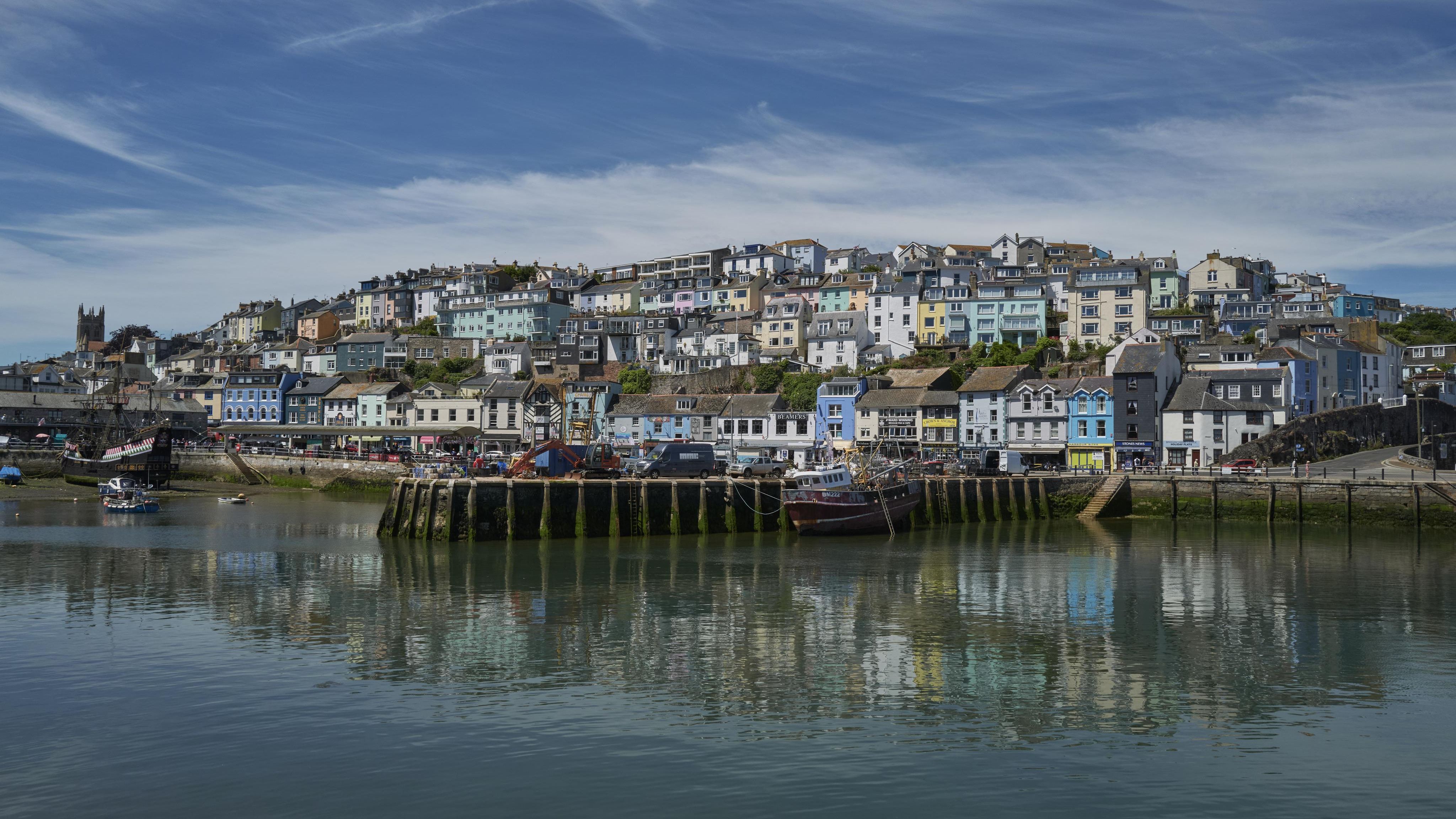 Colourful hillside houses overlooking a calm harbour with reflections on the water