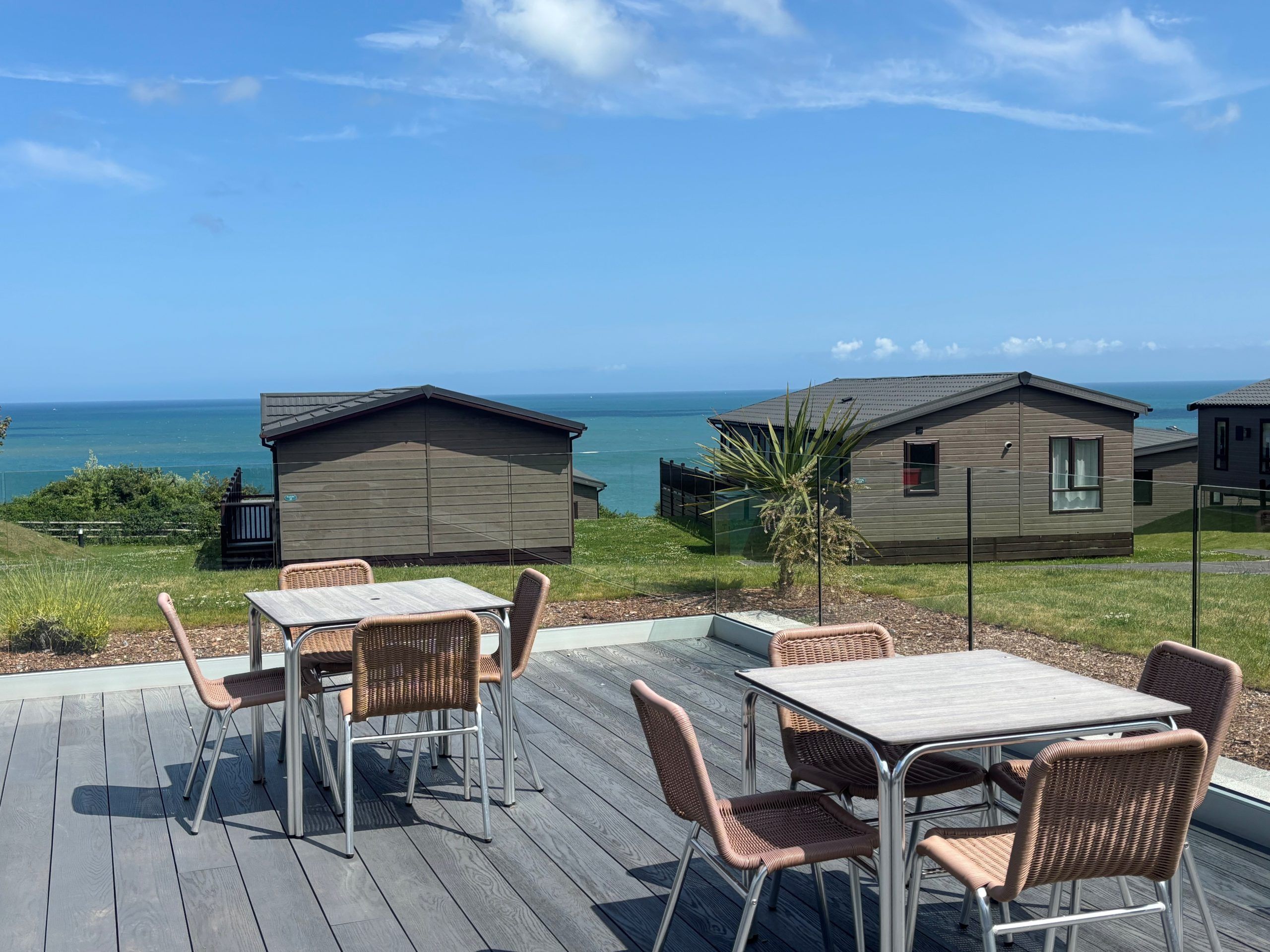 Outdoor patio seating with tables and chairs overlooking seaside holiday lodges and the ocean