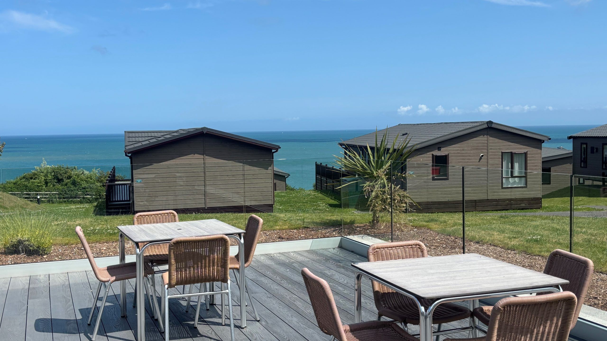 Outdoor patio seating with tables and chairs overlooking seaside holiday lodges and the ocean