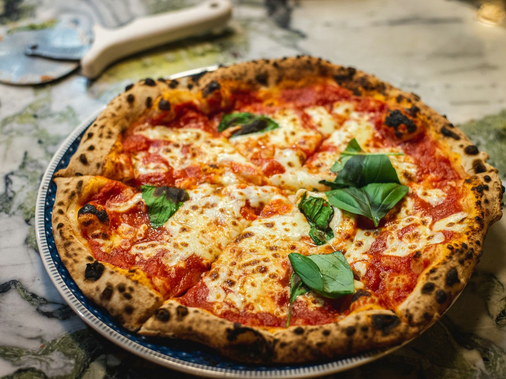 Margherita pizza with melted mozzarella and basil leaves on a plate