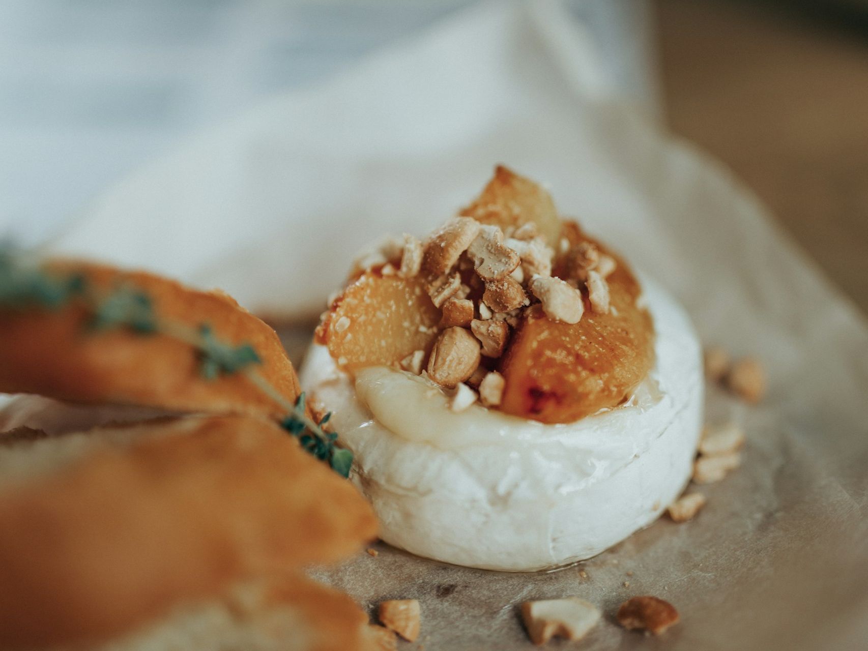 Baked cheese topped with apricots and crushed nuts, served with toasted bread
