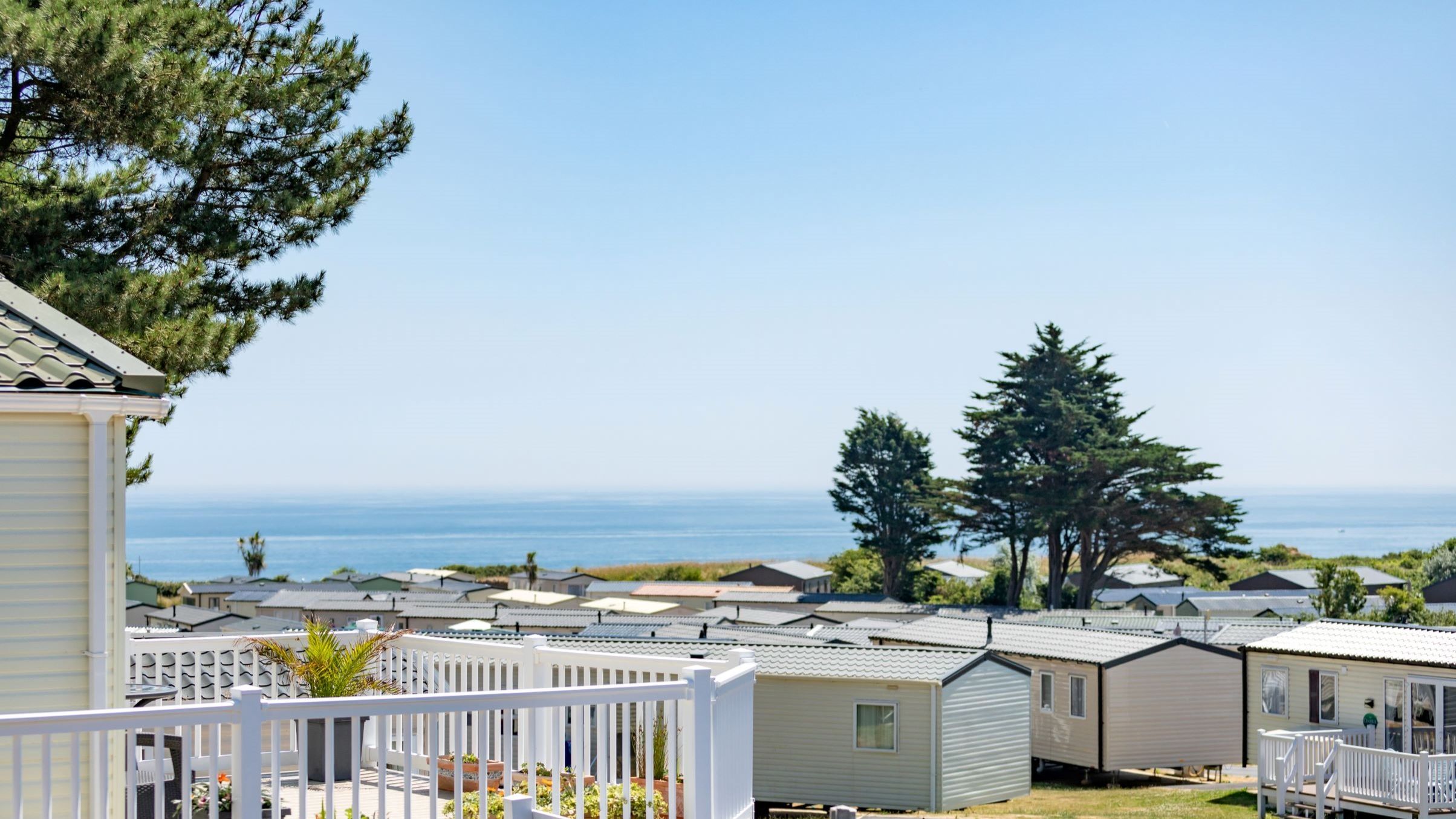 Holiday park caravans with sea view and trees on a sunny day