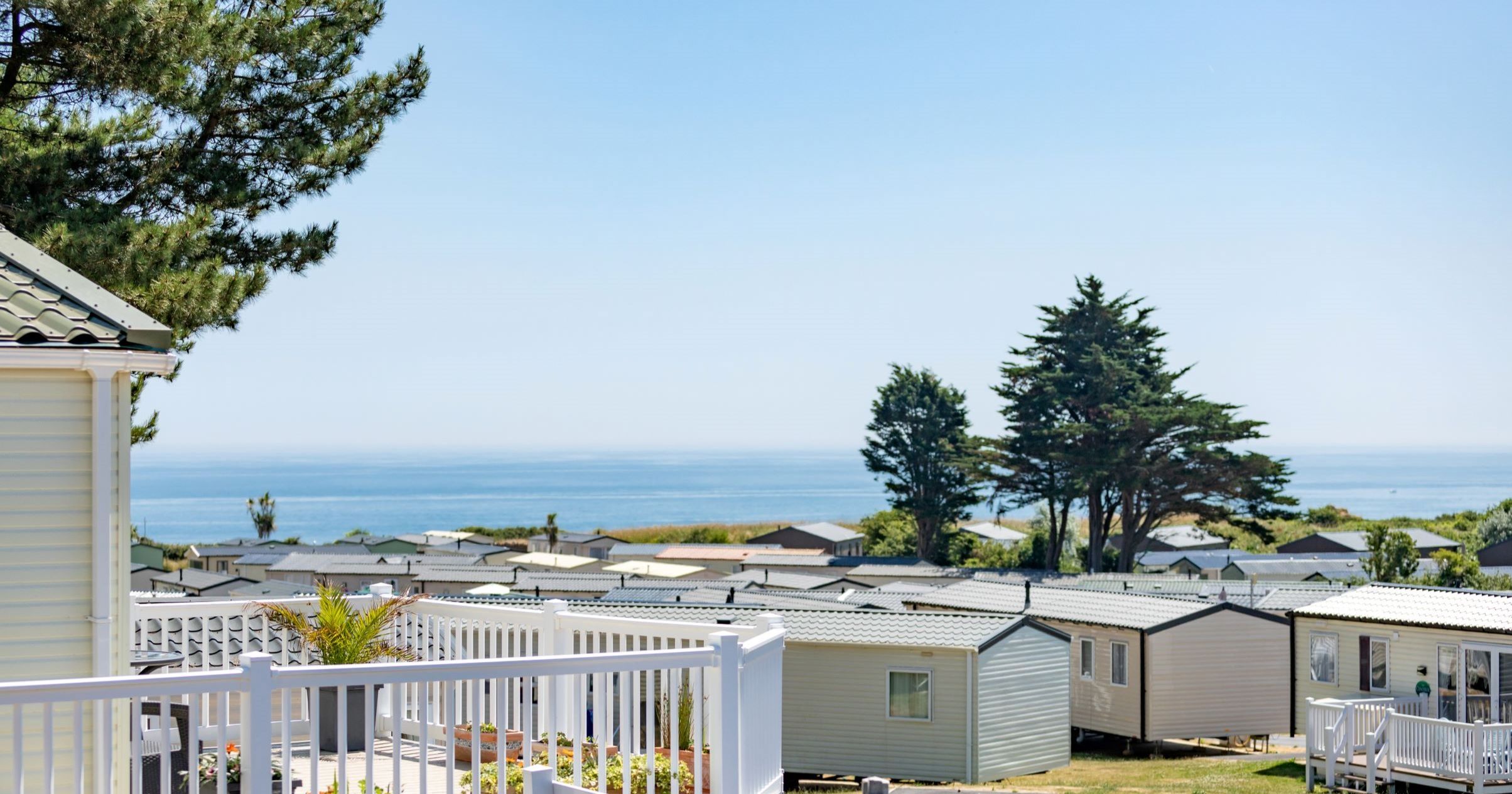 Holiday park caravans with sea view and trees on a sunny day
