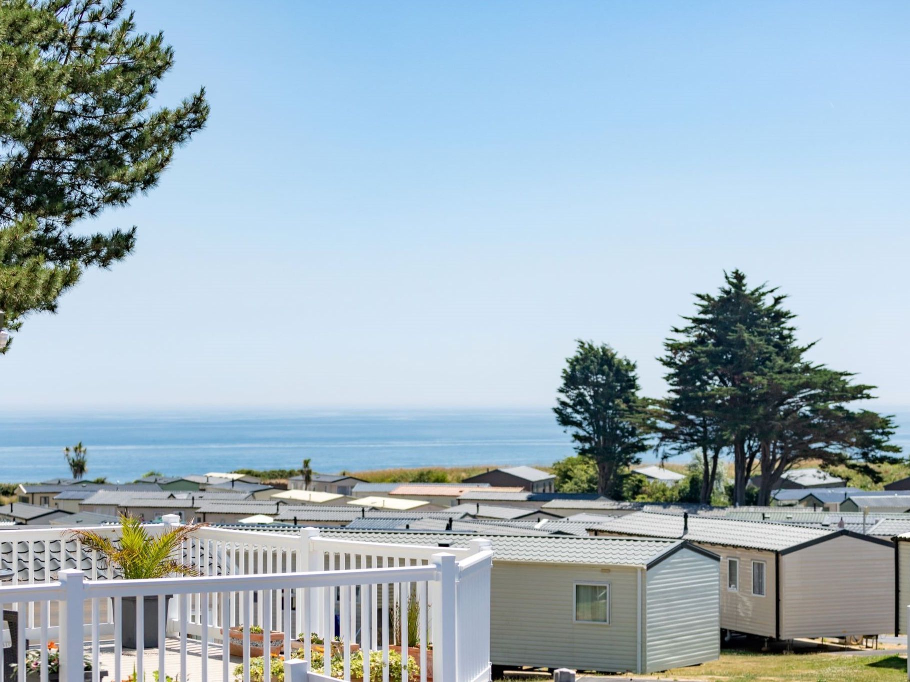 Holiday park caravans with sea view and trees on a sunny day