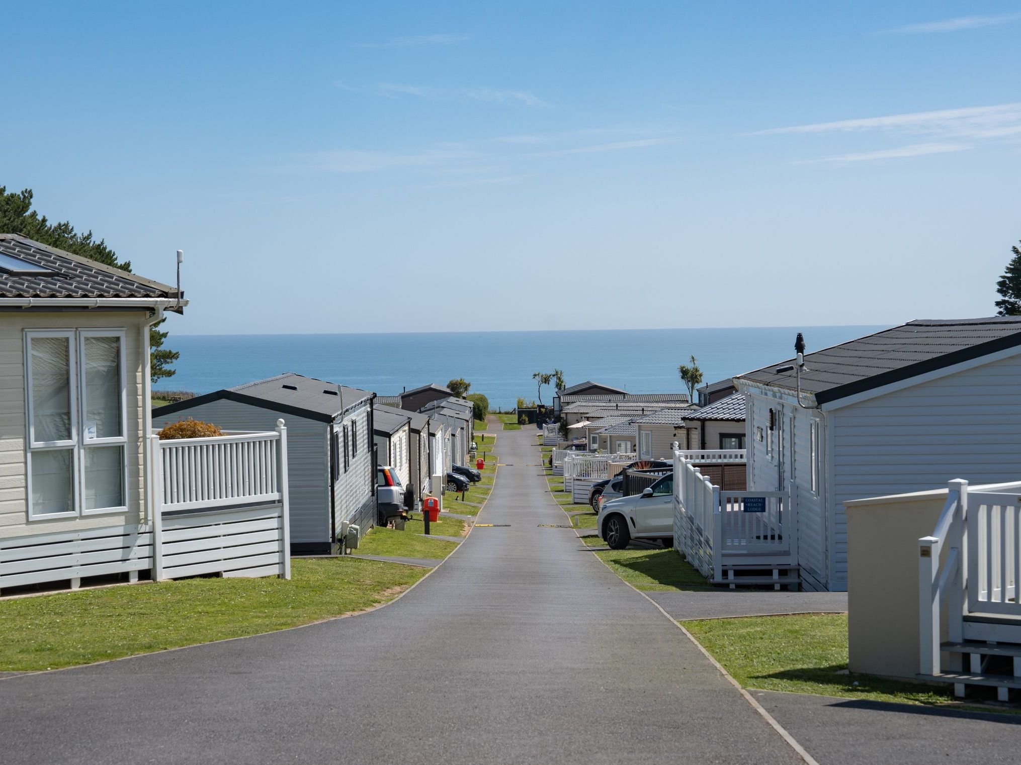 Road through a coastal holiday park with static caravans leading to the sea