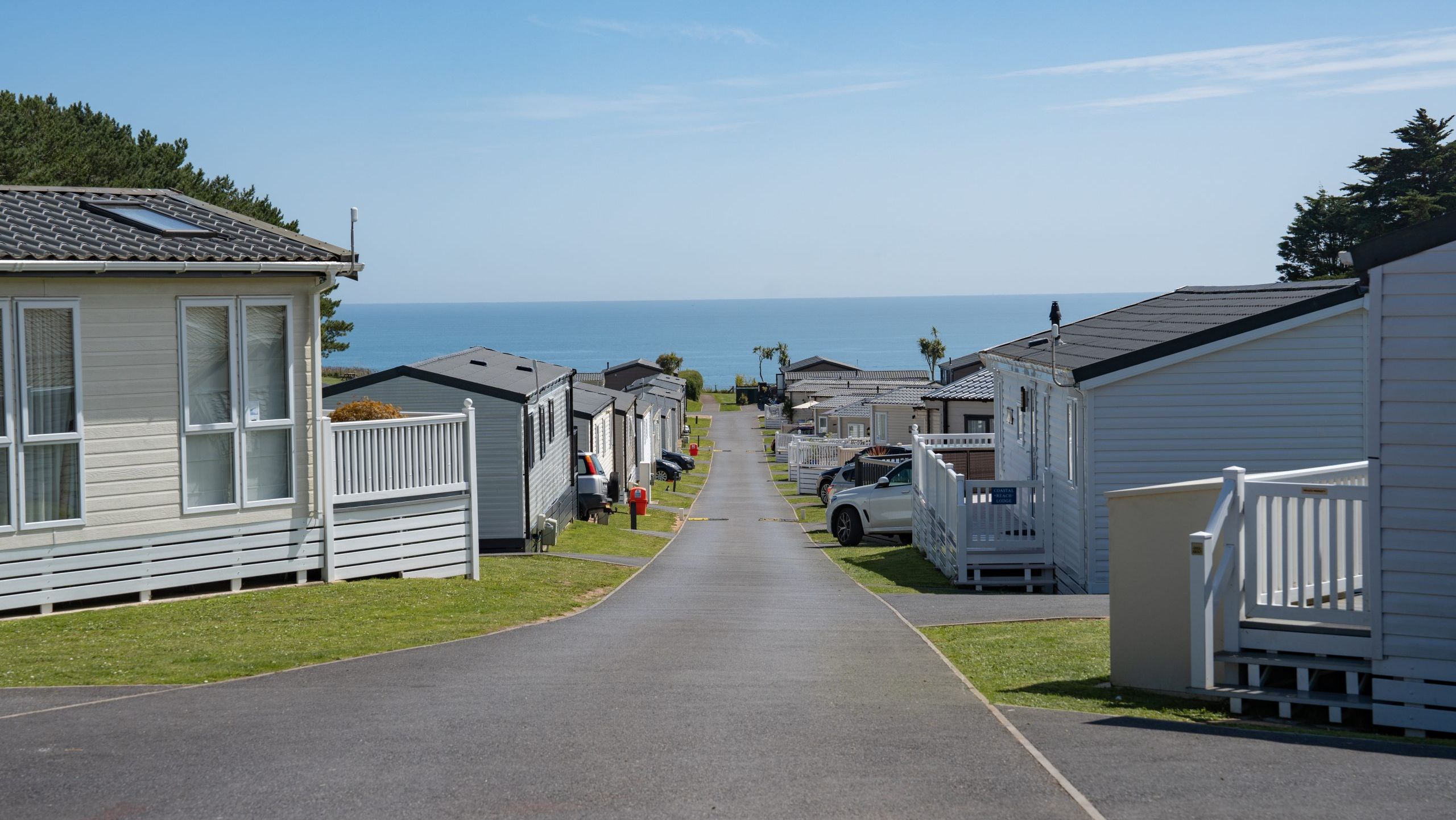 Road through a coastal holiday park with static caravans leading to the sea
