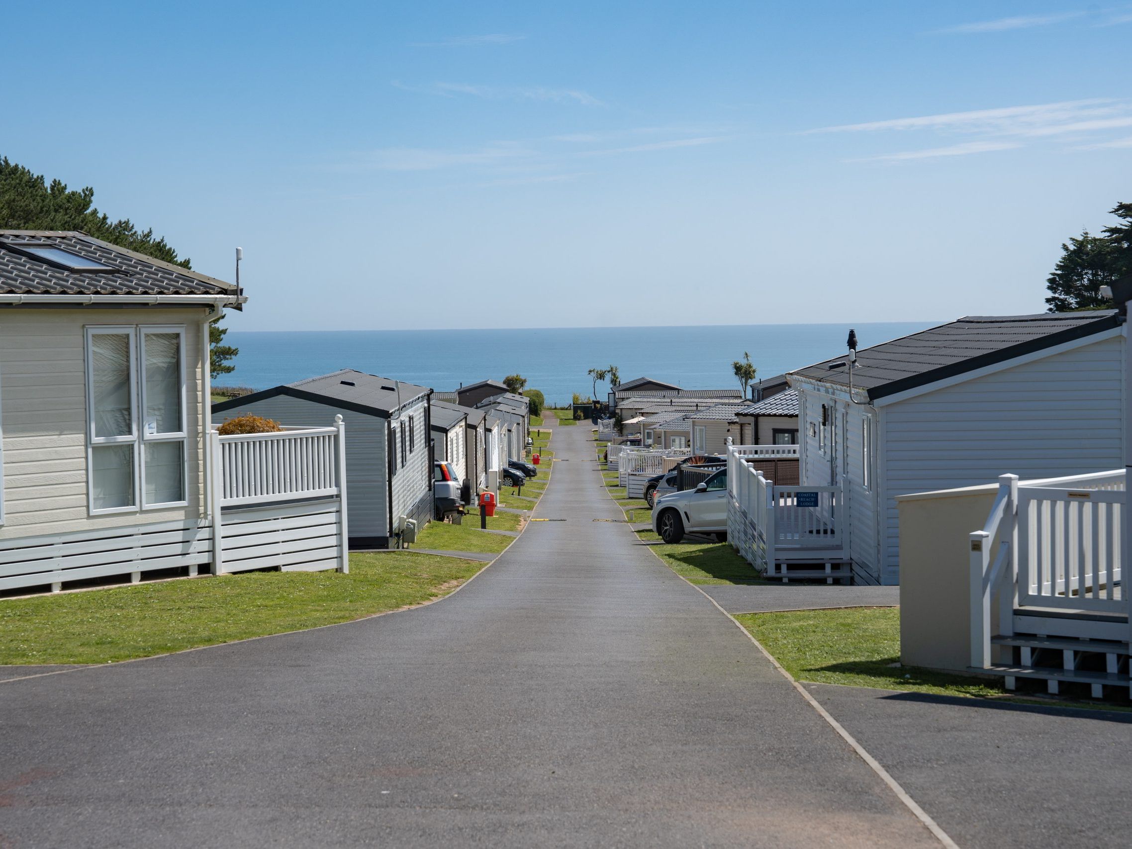 Road through a coastal holiday park with static caravans leading to the sea