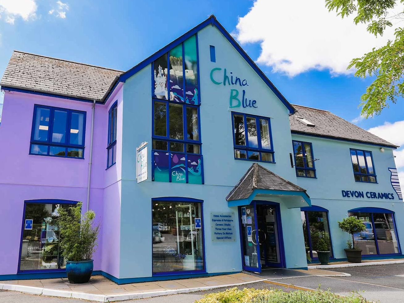 Exterior of the China Blue Devon Ceramics building with blue and purple walls and large windows under a bright sky