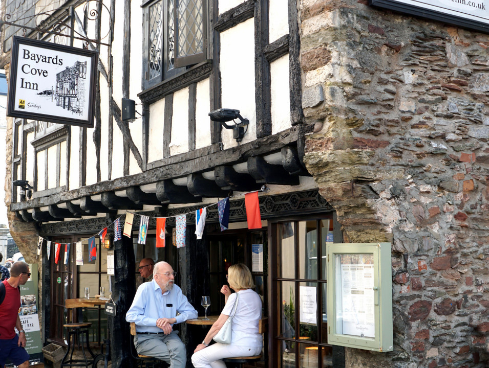 People sitting outside Bayards Cove Inn, a historic stone and timber building in town.