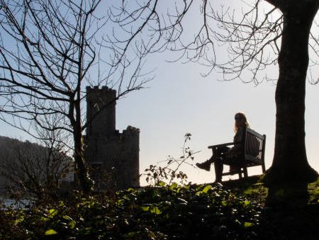 Lady sitting on bench near castle tower at Dartmouth.
